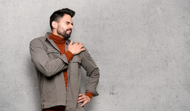 Bell&#39;uomo con la barba che soffre di dolore alla spalla per aver fatto uno sforzo sulla parete strutturata