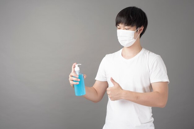 bell'uomo con maschera chirurgica sta usando disinfettante per le mani di alcol