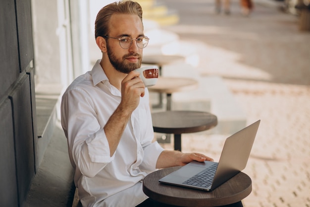 Bell'uomo d'affari che lavora online al computer dalla caffetteria