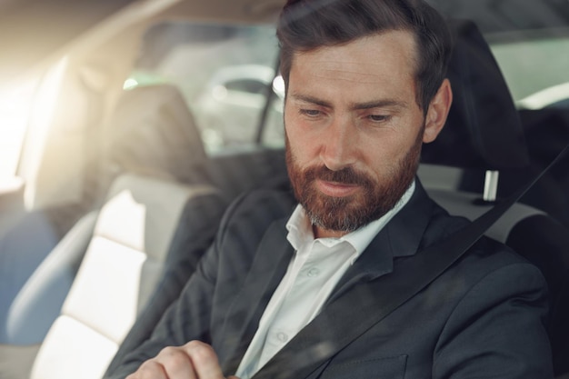 Bell'uomo d'affari in abito grigio sta guidando dietro il volante dell'auto