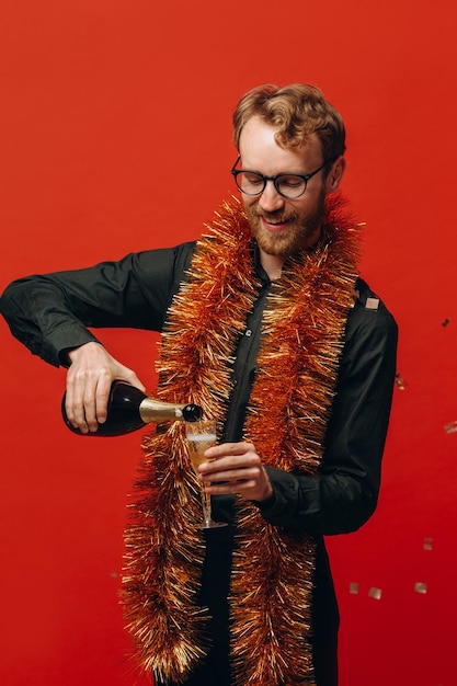 Bell'uomo dai capelli rossi con gli occhiali e un boa d'oro solleva un bicchiere di champagne Celebrazione del nuovo anno