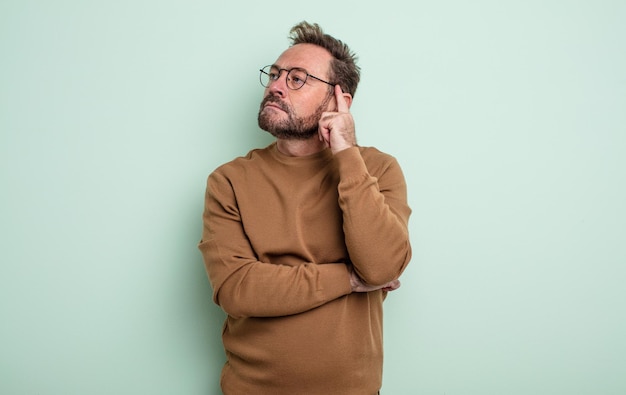 Bell'uomo di mezza età con uno sguardo concentrato, chiedendosi con un'espressione dubbiosa, guardando in alto e di lato