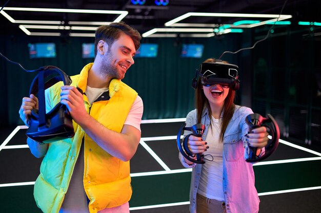 Bell'uomo e bella giovane donna con gli occhiali della realtà virtuale. VR, giochi, intrattenimento, concetto di tecnologia del futuro. Coppia con auricolare realtà virtuale divertirsi insieme.