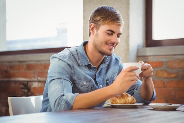 Bell&#39;uomo godendo caffè e croissant