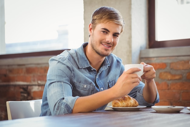 Bell&#39;uomo godendo caffè e croissant