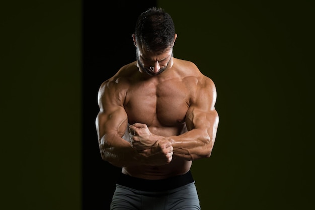 Bell'uomo in piedi forte in palestra e flettendo i muscoli Modello di fitness bodybuilder atletico muscolare in posa dopo gli esercizi