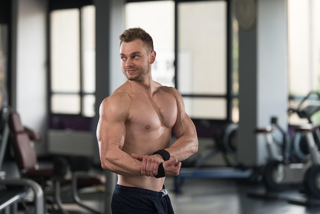 Bell'uomo in piedi forte in una moderna palestra e flettendo i muscoli Muscoloso atletico culturista modello di fitness in posa dopo gli esercizi