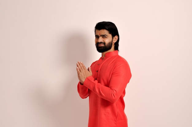 bell'uomo indiano che indossa kurta sorridente facendo il gesto di Namaste con le mani vista laterale