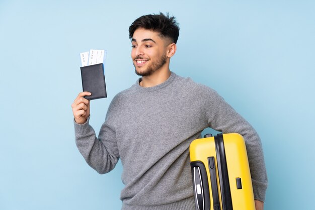 bell'uomo isolato su blu in vacanza con la valigia e il passaporto