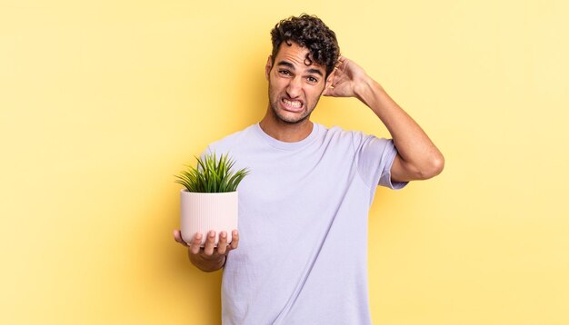 Bell'uomo ispanico che si sente stressato, ansioso o spaventato, con le mani sulla testa. concetto di pianta decorativa