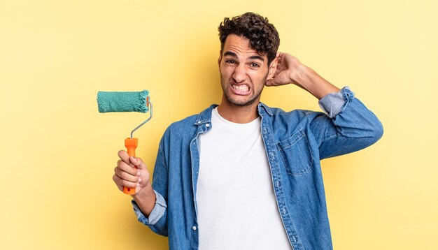 Bell'uomo ispanico che si sente stressato, ansioso o spaventato, con le mani sulla testa. concetto di vernice a rullo