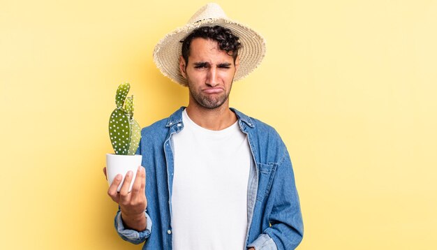 Bell'uomo ispanico che si sente triste e lamentoso con uno sguardo infelice e piange il concetto di contadino e cactus