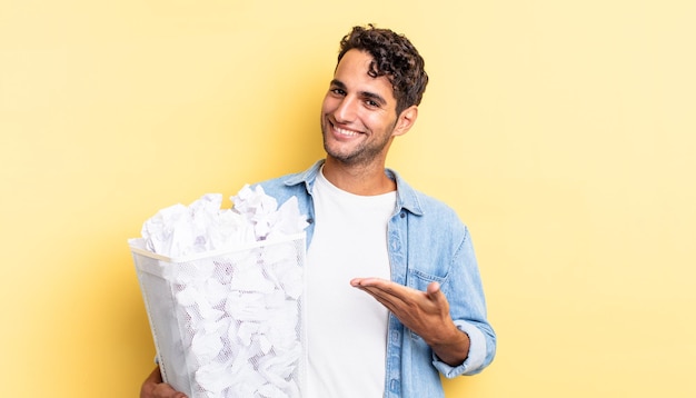 Bell'uomo ispanico che sorride allegramente, si sente felice e mostra un concetto. concetto di spazzatura delle palle di carta