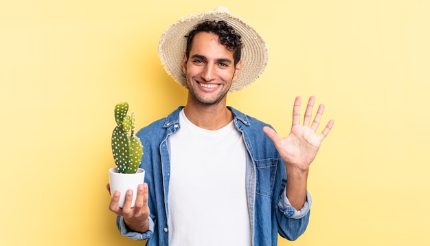 Bell'uomo ispanico che sorride e sembra amichevole, mostrando il concetto numero cinque di agricoltore e cactus