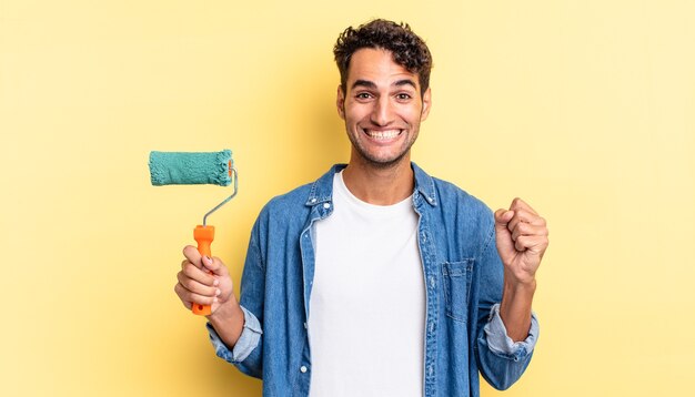 bell'uomo ispanico sentirsi scioccato, ridere e celebrare il successo. concetto di vernice a rullo