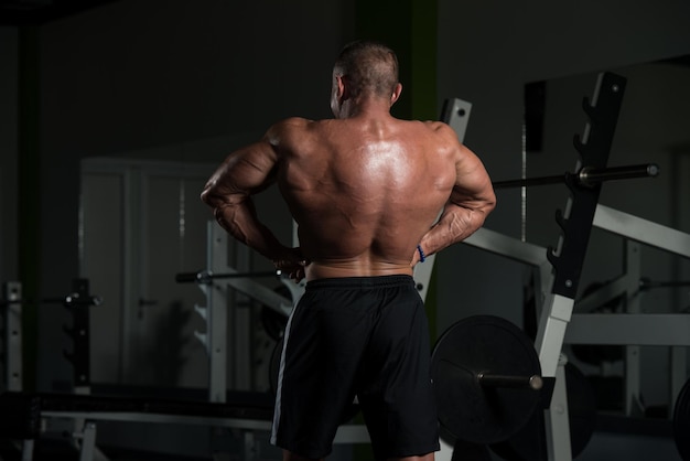 Bell'uomo maturo in piedi forte in palestra e flettendo i muscoli Muscoloso bodybuilder atletico Fitness maschile in posa dopo gli esercizi