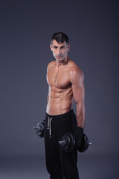 Bell'uomo muscoloso che lavora con i manubri Istruttore di fitness personale Allenamento personale