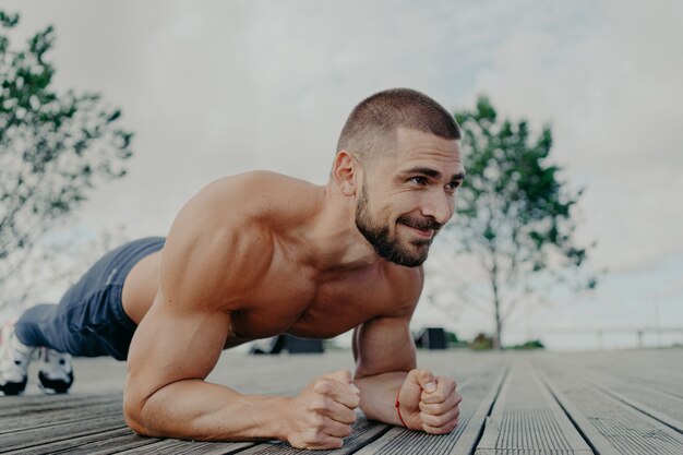 Bell'uomo muscoloso con il torso nudo all'aperto facendo allenamento fitness