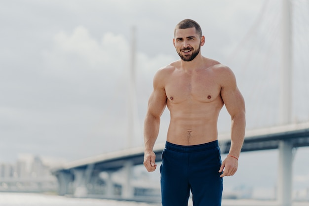 Bell'uomo muscoloso con il torso nudo all'aperto facendo allenamento fitness