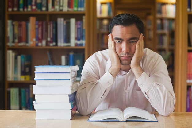 Bell&#39;uomo seduto di fronte a un libro aperto in biblioteca