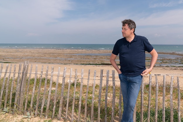 Bell'uomo sulla spiaggia che guarda lato in estate Oceano Atlantico a Ile de Re in Francia