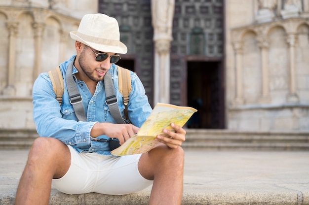 Bell'uomo turistico che punta alla mappa cercando la direzione del concetto di viaggio di destinazione viaggio indietro...