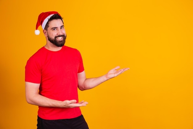 Bell'uomo vestito per natale che indossa il cappello di babbo natale che punta allo spazio di testo libero. promozione di fine anno