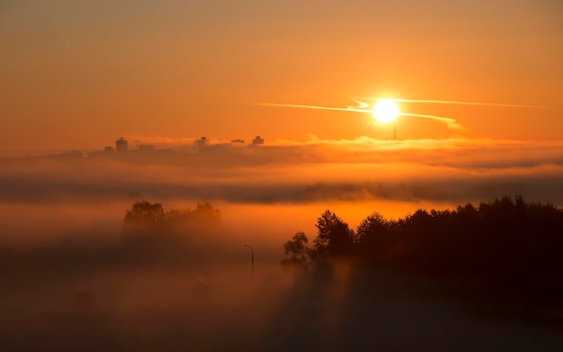 Bella alba luminosa, il sole sorge sulla città, la luce passa attraverso la nebbia.