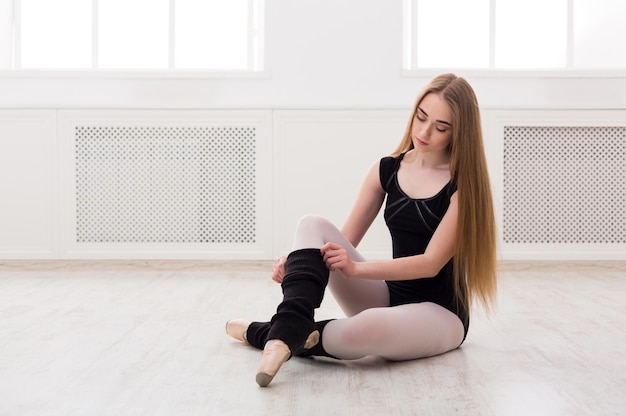 Bella ballerina graziosa in nero che si estende sullo sfondo dell'aula. Corso di danza classica, copia spazio