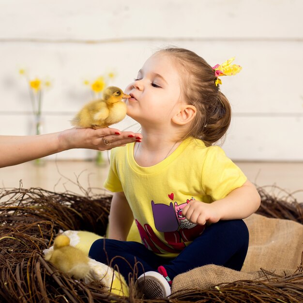 Bella bambina bacia un simpatico anatroccolo soffice di Pasqua.