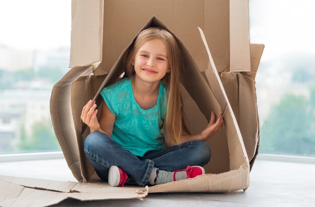 Bella bambina bionda che gioca nella scatola di spedizione