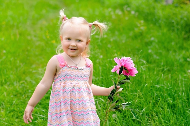 bella bambina bionda con fiore di peonia