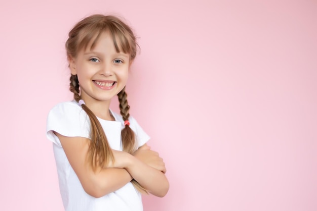 Bella bambina bionda con i capelli lunghi in maglietta bianca sorridente su sfondo rosa