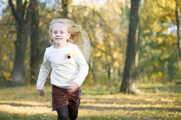 Bella bambina bionda corre in un parco d'autunno Un bambino in una passeggiata in autunno