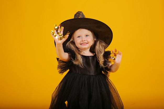 bella bambina bionda in un vestito nero e un cappello da strega halloween