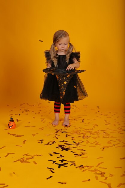 bella bambina bionda in un vestito nero in leggings neri e rossi un cappello da strega halloween