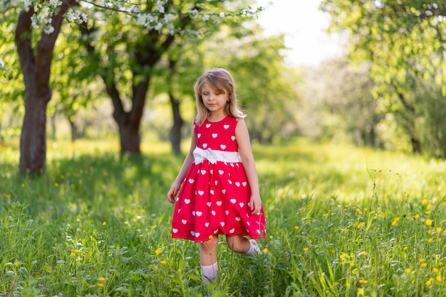 Bella bambina cammina nel giardino tra gli alberi in primavera