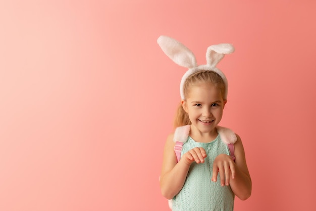 Bella bambina carina con orecchie da coniglio pasquale sorridente su sfondo rosa Cartolina di Pasqua