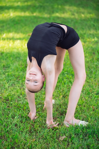 Bella bambina che fa ginnastica sull'erba un giorno soleggiato