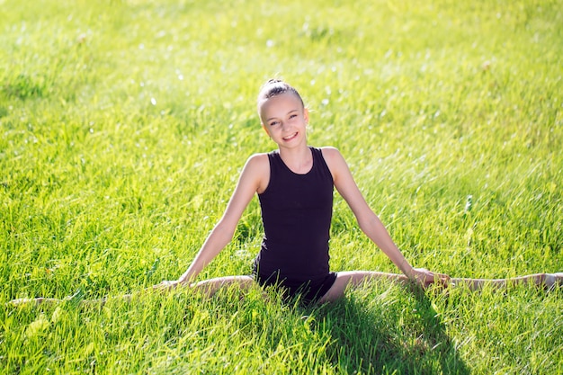 Bella bambina che fa ginnastica sull'erba un giorno soleggiato