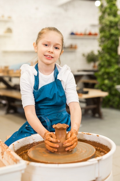 bella bambina che fa una pentola di argilla in un laboratorio di ceramica