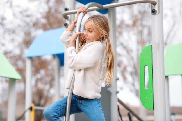 Bella, bambina che gioca nel parco giochi per bambini, pronta a scivolare dal polo.