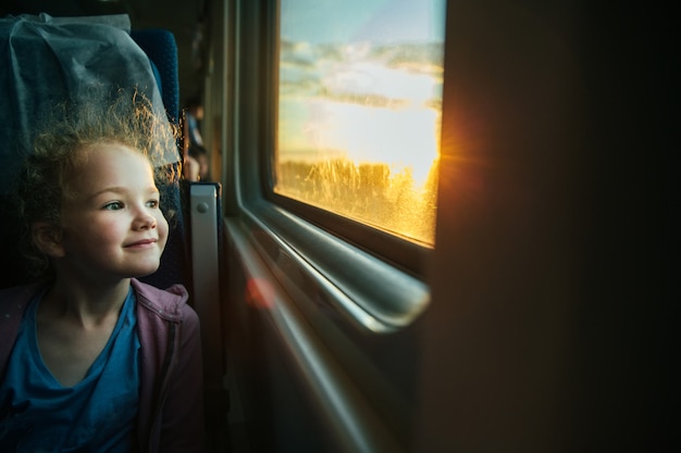 Bella bambina che guarda fuori finestra del treno al di fuori