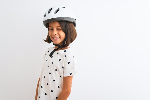 Bella bambina che indossa il casco da bici di sicurezza in piedi su sfondo bianco isolato ammiccante guardando la telecamera con espressione sexy faccia allegra e felice