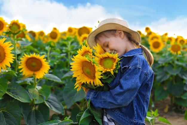 Bella bambina che si gode la natura Bambino femmina sorridente felice in piedi nel campo di girasoli