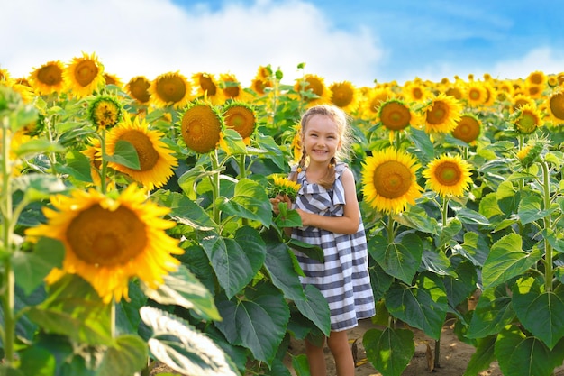 Bella bambina che si gode la natura Bambino femmina sorridente felice in piedi nel campo di girasoli