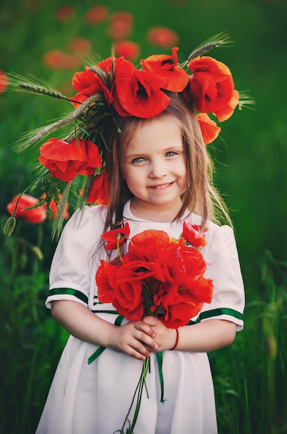 Bella bambina che tiene un mazzo di fiori di campo rossi