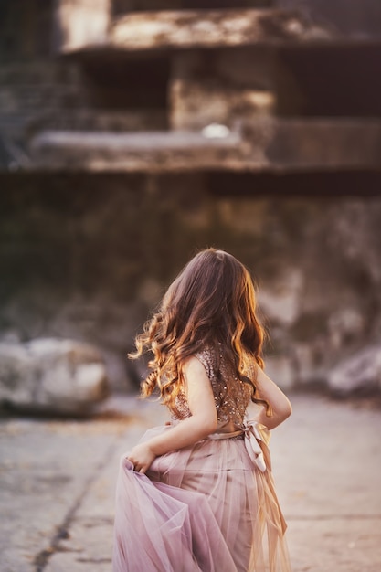 Bella bambina con i capelli lunghi in elegante abito marrone run