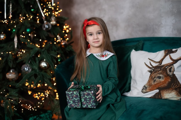 Bella bambina con regalo di Natale su sfondo di luci di Natale