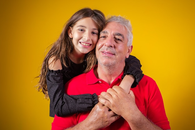 Bella bambina con suo padre più anziano su sfondo giallo. Festa del papà